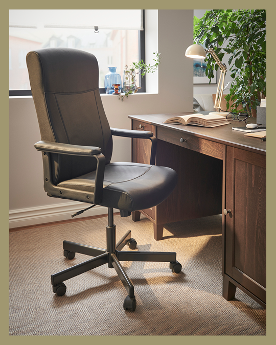 Una silla de escritorio con respaldo alto y ruedas frente a un escritorio.