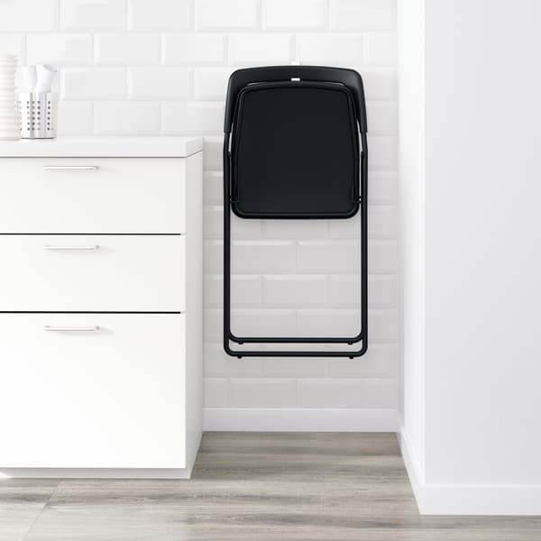 Una silla plegable colgada al costado de un mueble de cocina.