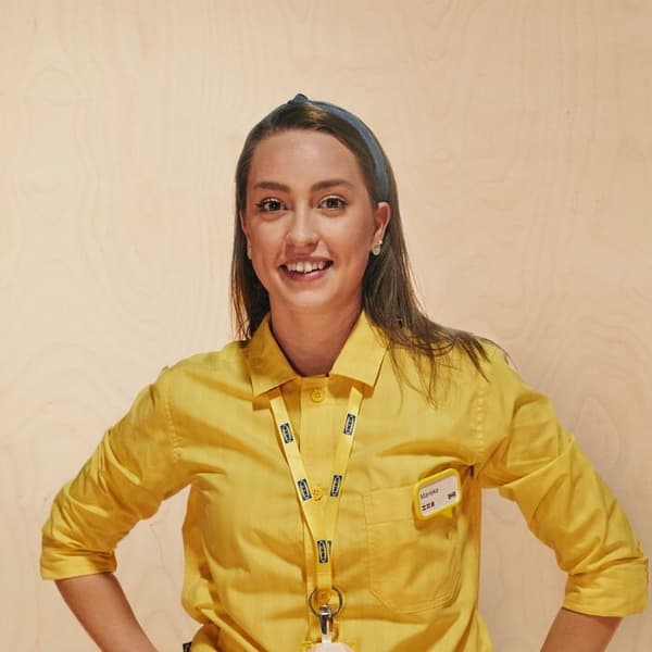 Una sorridente dipendente IKEA con un camice giallo