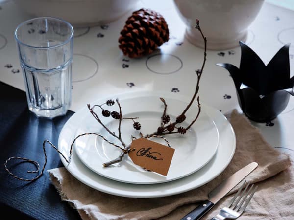 Una tavola apparecchiata per il Natale con un segnaposto, posate e un bicchiere vuoto.