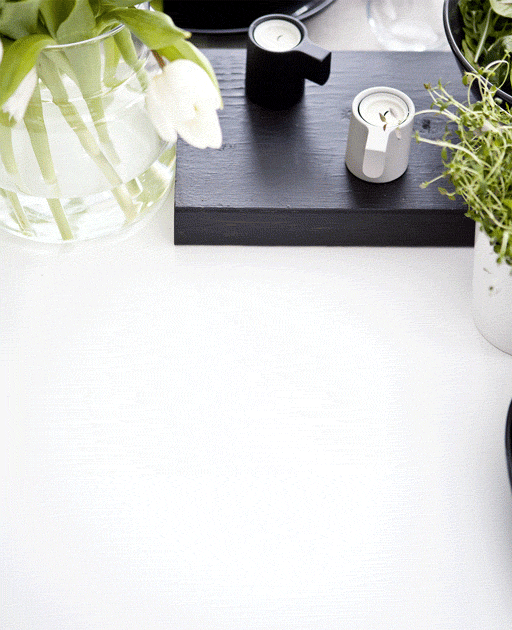 Una tavola in bianco e nero decorata con un tovagliolo di carta verde, fiori in un vaso ed erbe aromatiche in un portavasi bianco - IKEA