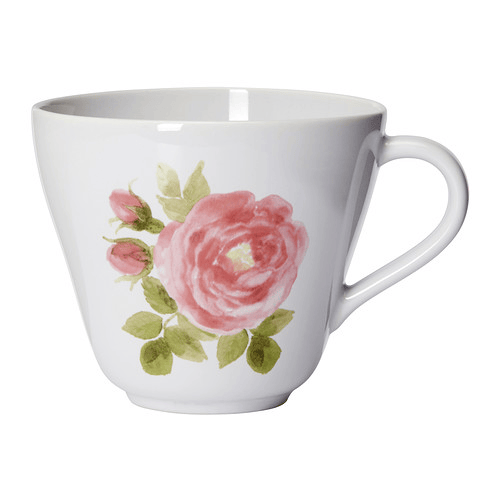 Una taza grande blanca con una rosa rosada y pétalos verdes pintados sobre un fondo blanco.