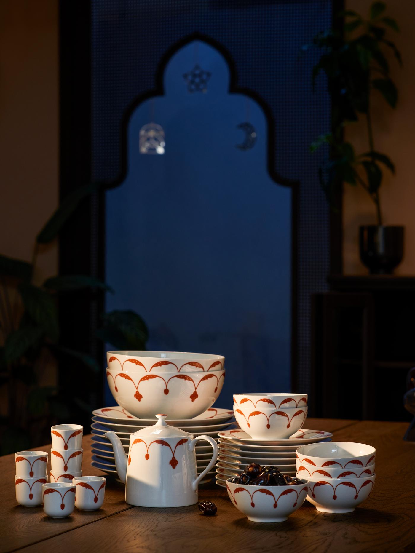 Una tetera y tazas para kava GOKVÄLLÅ junto a varias pilas de platos y cuencos GOKVÄLLÅ.