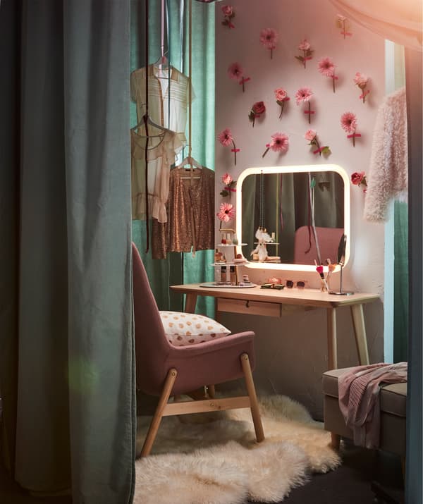 Una zona para el maquillaje con una pared de flores y un espejo STORJORM con iluminación integrada.