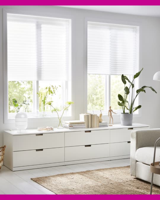 Unas cortinas plisadas cubren las ventanas de un dormitorio.