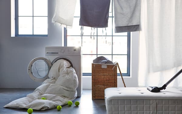 Un'asciugatrice da cui esce un piumino, un cestone della biancheria aperto e un materasso su cui poggia un aspirapolvere - IKEA