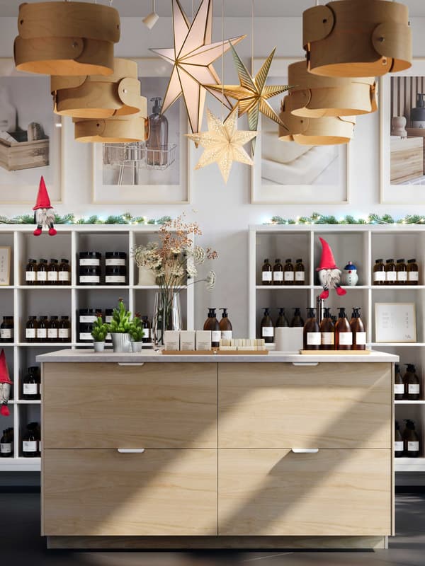 Un'attività commerciale con un bancone e degli scaffali con prodotti in vendita. Il negozio è decorato per le feste con prodotti delle collezioni STRÅLA e VINTERFINT.