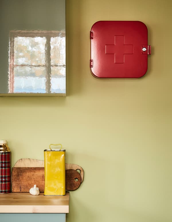 Une armoire à pharmacie rouge accrochée à un mur de cuisine à côté d’une armoire de cuisine.