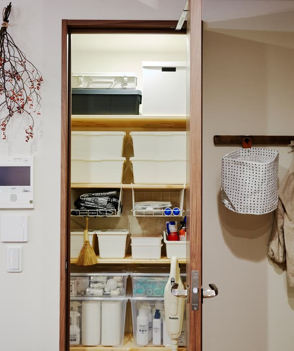 Une armoire ouverte avec des boîtes de rangement blanches empilées sur des tablettes intérieures.