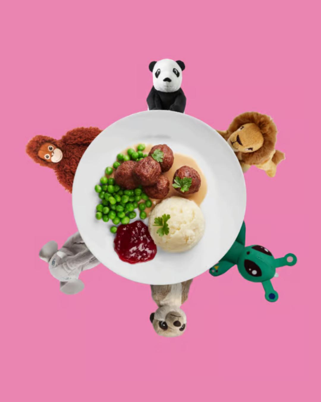 une assiette de boulettes, petits pois, sauces et purée avec des peluches autour