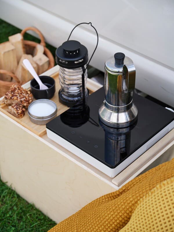 Une cafetière posée sur le concentrateur à induction portable TILLREDA, avec une lanterne solaire à côté.