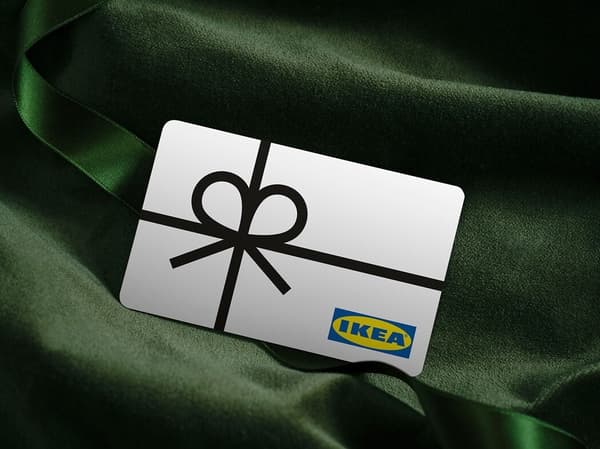 Une carte cadeau IKEA est posée sur un tissu de soie vert