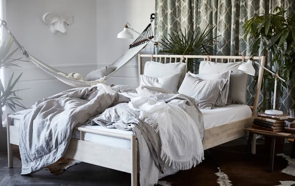 Une chambre à coucher avec le cadre de lit BJÖRKSNÄS, la lampe RANARP et la table basse STOCKHOLM.