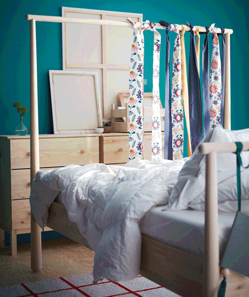 Une chambre à coucher avec une housse de couette IKEA SOMMARASTER et des taies d’oreiller aux grandes fleurs multicolores sur fond blanc.