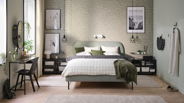 Une chambre avec des meubles verts et noirs, des affiches encadrées et un lit capitonné Gunnared vert sauge.