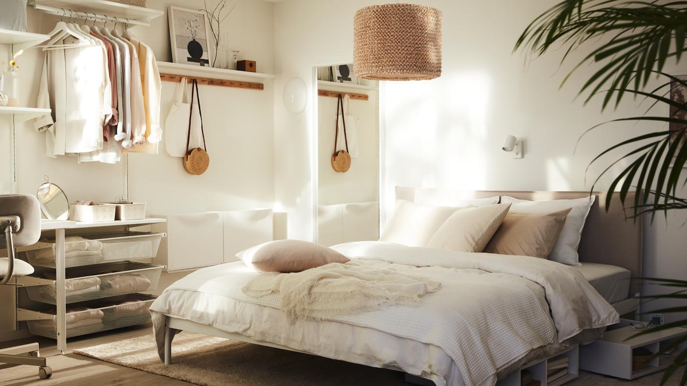 Une chambre ensoleillée avec un lit KLEPPSTAD garni de linge de lit ÄNGSLILJA blanc et surmonté d’une suspension LERGRYN.