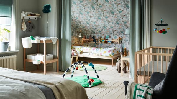 Une chambre familiale composée d’un lit double, d’un lit SNIGLAR, d’un lit bébé et d’une table à langer, avec des rideaux pour créer un espace personnel.