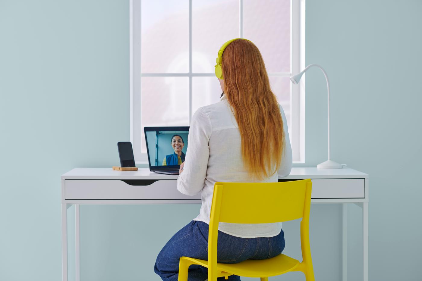 Une cliente sur son bureau avec un casque et son ordinateur en visio