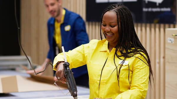 Une collaboratrice IKEA portant une chemise jaune ferme un emballage avec un pistolet à colle.