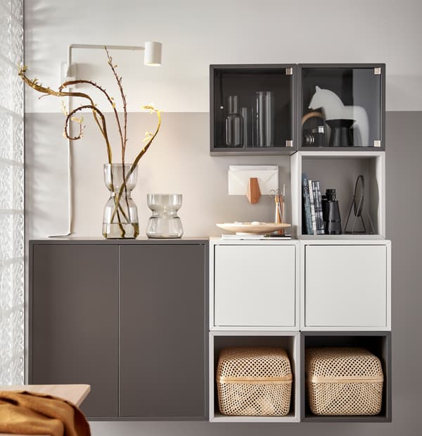 Une combinaison d’unités de rangement EKET blanches et grises avec deux boîtes de rangement SMARRA, deux vases en verre et des objets personnels.