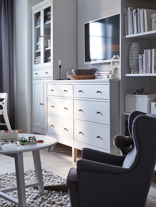 Une commode 6 tiroirs IDANÄS blanche entre une armoire haute à portes vitrées IDANÄS blanche et une bibliothèque IDANÄS blanche.