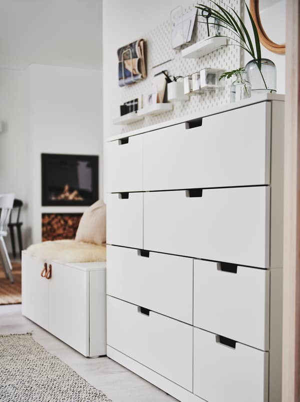 Une commode NORDLI blanche adossée à un mur blanc près de l’entrée d’une pièce à aire ouverte.