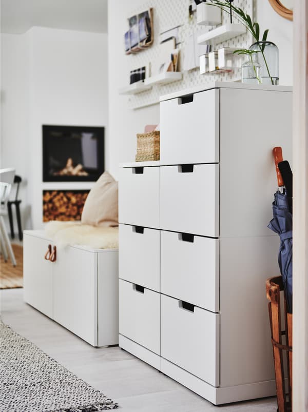 Une commode NORDLI blanche contre un mur blanc près de l’entrée d’un intérieur en plan ouvert.