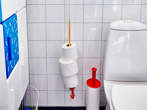 Une corde suspendue à côté du WC sert de porte-rouleaux. Une section peinte en rouge, dans le bas, indique quand il faut refaire les stocks.