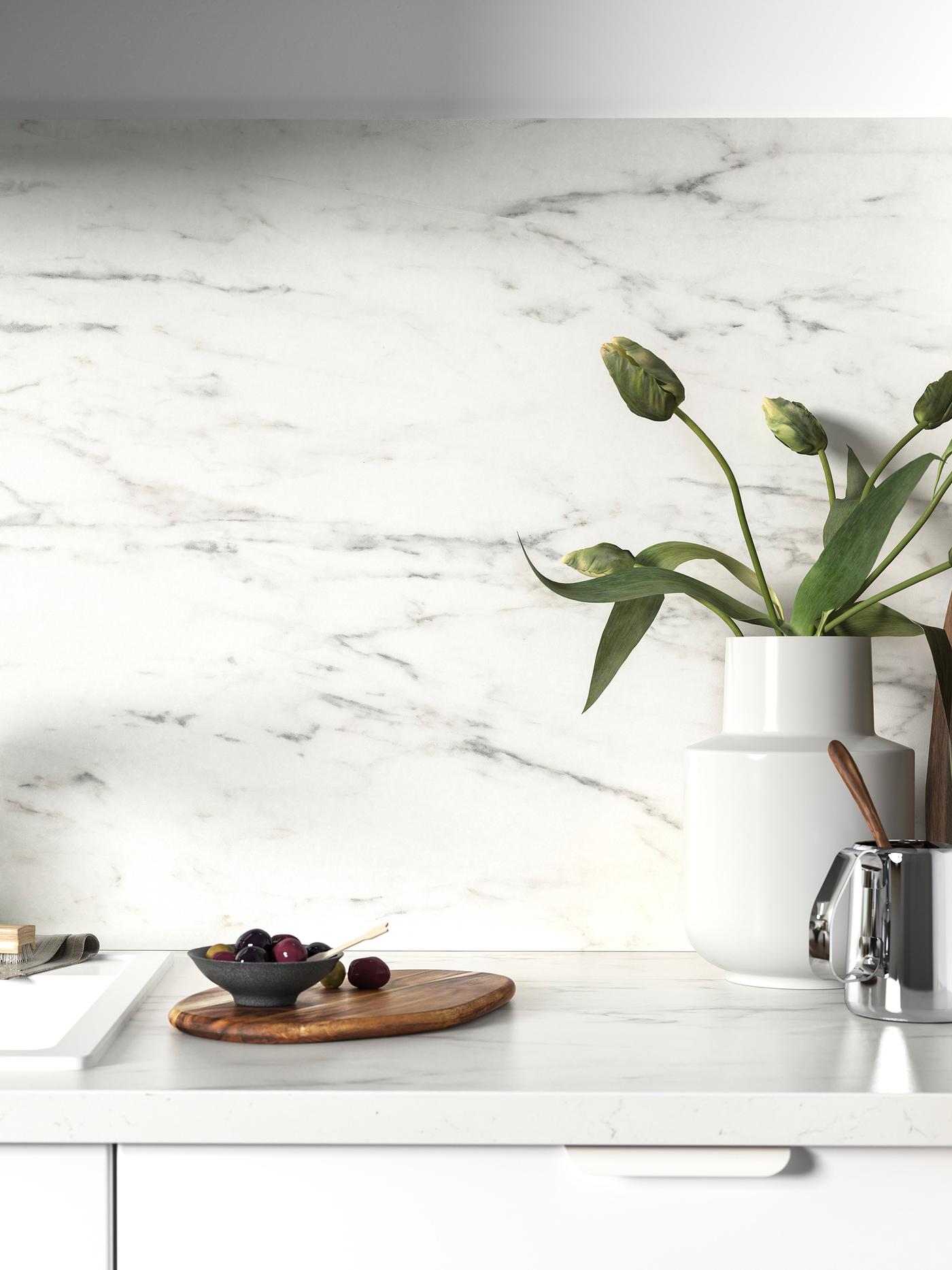 Une crédence blanche et un plan de travail au motif marbre blanc forment un tout harmonieux. Sur le plan de travail, un vase blanc garni de fleurs.