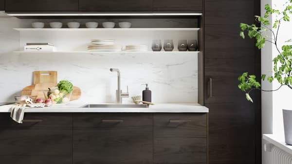 Une cuisine ASKERSUND en effet frêne brun foncé, avec un plan de travail EKBACKEN en effet marbre sur lequel sont posés des planches à découper et des légumes.