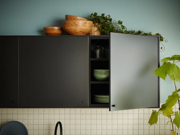 Une cuisine avec des façades de cuisine IKEA KUNGSBACKA noires, fabriquées à partir de bois et de bouteilles en plastique PET recyclés.