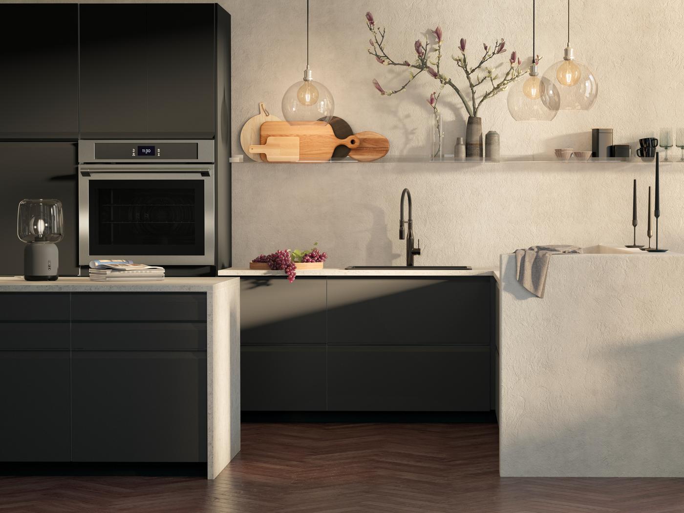 Une cuisine avec des façades de tiroir UPPLÖV anthracite mat, des abat-jour JAKBSBYN et un four mural TÄNGBY en acier inoxydable.