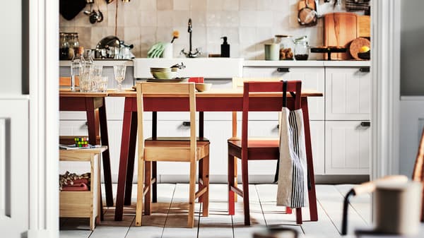 Une cuisine avec faces de tiroir STENSUND blanches et deux tables PINNTORP entourées de chaises PINNTORP.