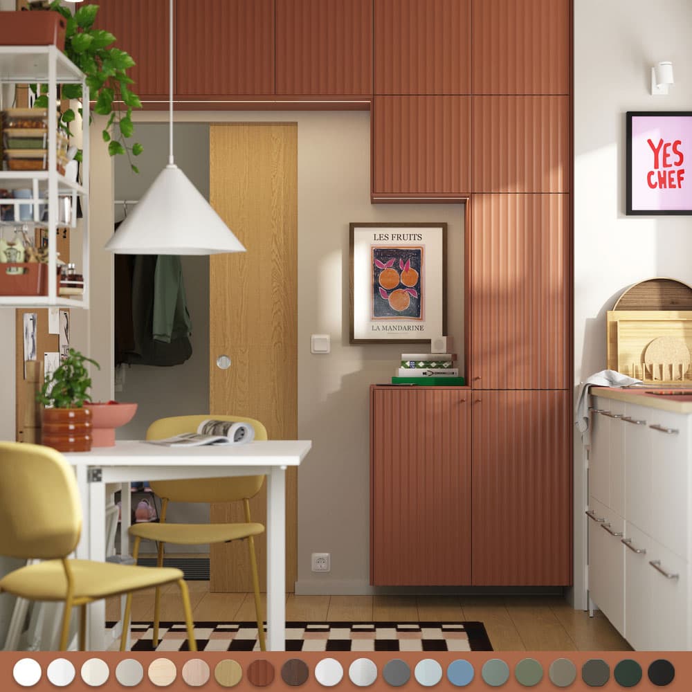 Une cuisine couleur terracotta avec une partie en blanc, des chaises jaunes et une table à déjeuner blanche.