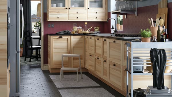 Une cuisine en coin munie de portes vitrées en frêne naturel et d’un comptoir en quartz noir à effet minéral scintillant.