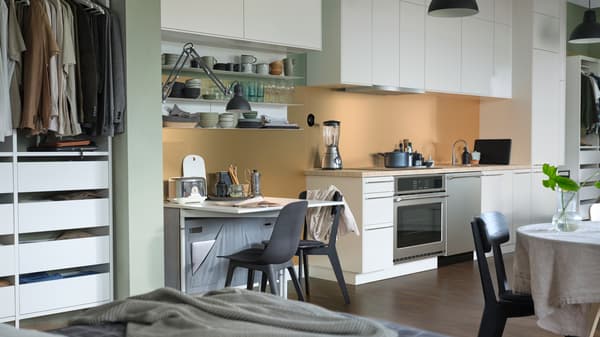 Une cuisine équipée d’armoires SEKTION blanches, de chaises ODGER anthracite et d’un comptoir stratifié SÄLJAN beige à effet pierre.