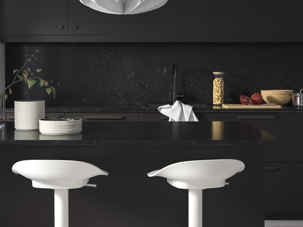 Une cuisine noire avec des chaises hautes blanches