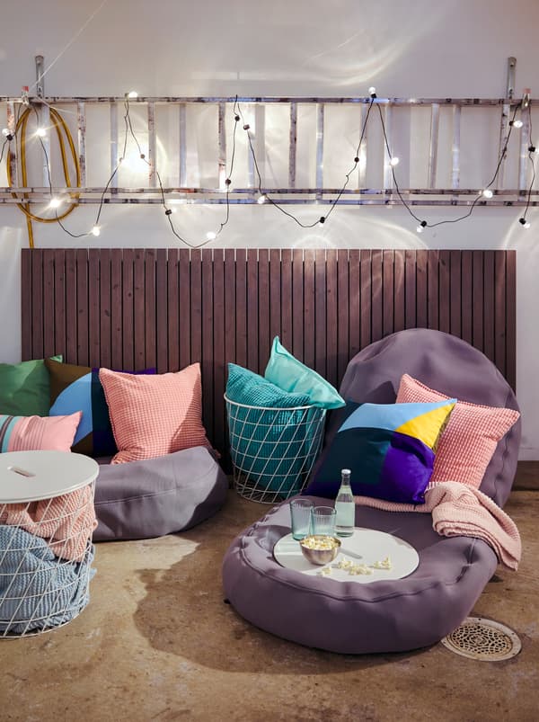 Une dalle de béton rugueux recouverte de fauteuils poires BUSSAN et de coussins avec plus de textiles dans des tables de rangement KVISTBRO.