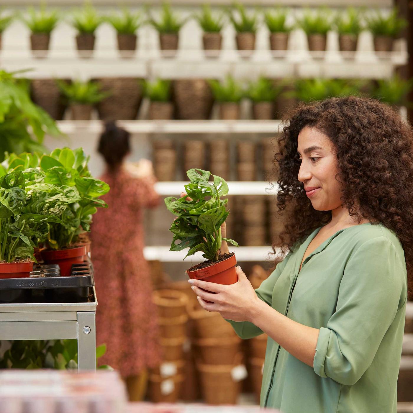 Une dame tient une plante dans la magasin IKEA.