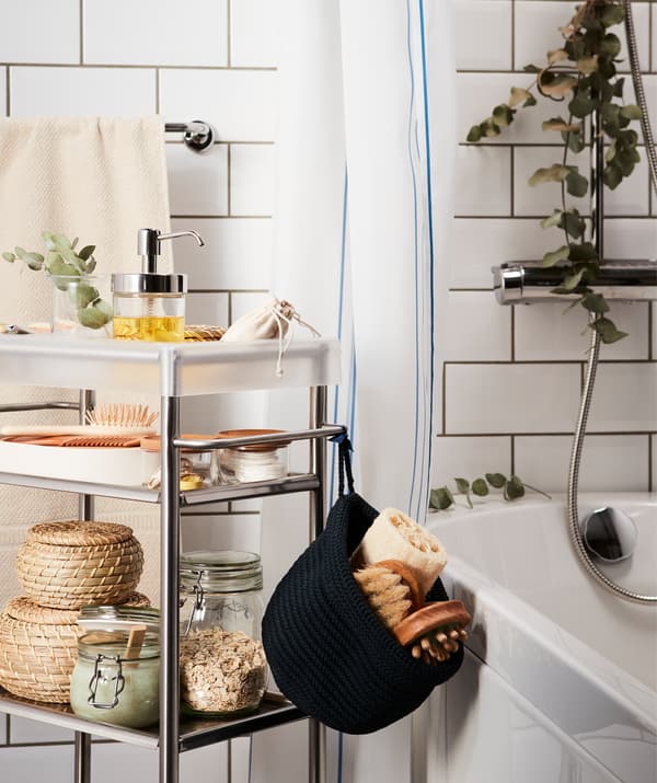Une desserte présentant tout le nécessaire pour s’offrir un spa maison est placée près de la baignoire. Des branches d’eucalyptus décorent la pièce.