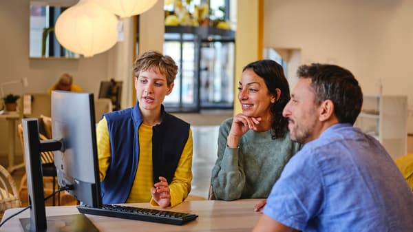 Une employée IKEA assiste deux clients lors d'un rendez-vous de planification et leur montre une solution sur un écran.