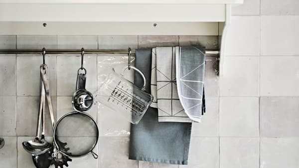 Une étagère de cuisine blanche avec des ustensiles accrochés.