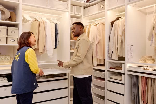 Une experte IKEA de La Rochelle conseillant un client sur la conception d'un dressing PAX, présentant des solutions de rangement personnalisées et des accessoires dans un espace lumineux.