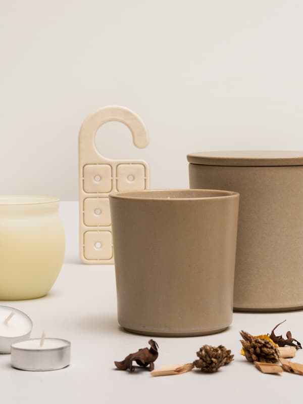 Une exposition de plusieurs bougies parfumées à la vanille JÄMLIK, du pot-pourri et un cintre parfumé contre un fond blanc.