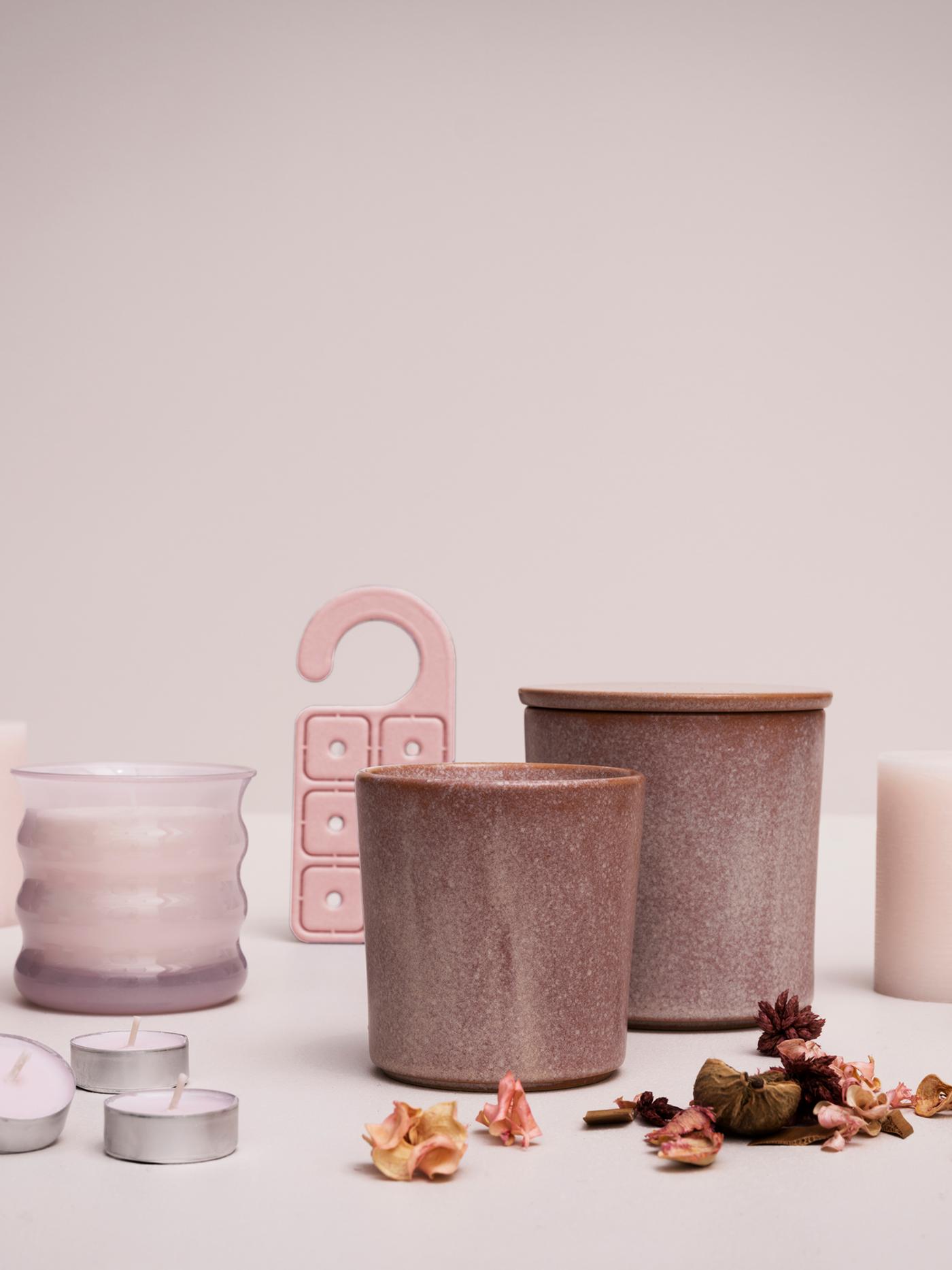 Une exposition de plusieurs bougies parfumées au jasmin LUGNARE, du potpourri et un cintre parfumé contre un fond rose pâle.