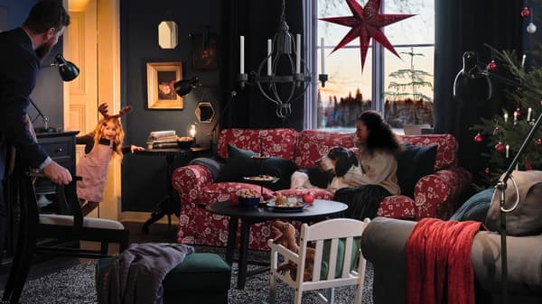 Une famille et son chien sont assis dans leur salon, attendant qu'une petite fille, regardant à travers la porte, fasse un spectacle.