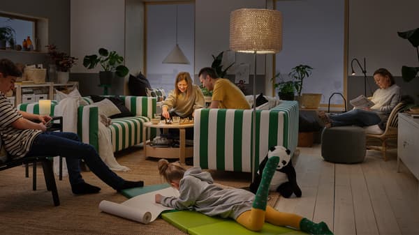 Une famille passe du temps ensemble à la maison. Une suspension NÄVLINGE, une lampe de table ISBRYTARE et un lampadaire NÄVLINGE éclairent la pièce.