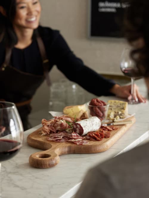 Une femme assise en face d'une planche de charcuterie à un bar.
