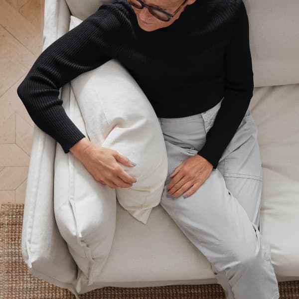 Une femme assise sur une canapé, tenant un oreiller dans sa main