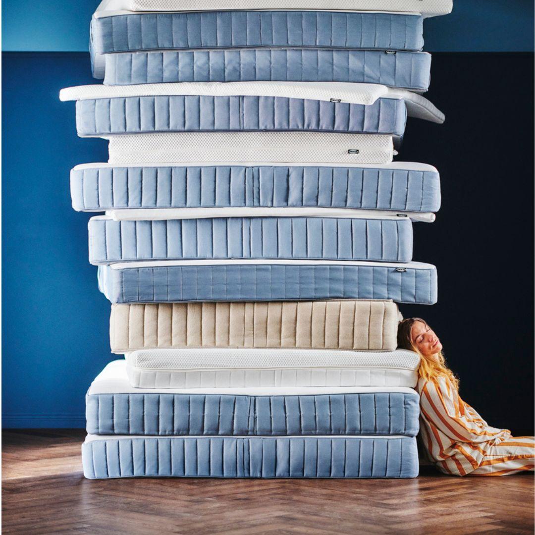 Une femme est allongée contre une pile de matelas et dort.